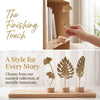 A set of metallic botanical ornaments featuring ginkgo leaves displayed on a wooden tray.