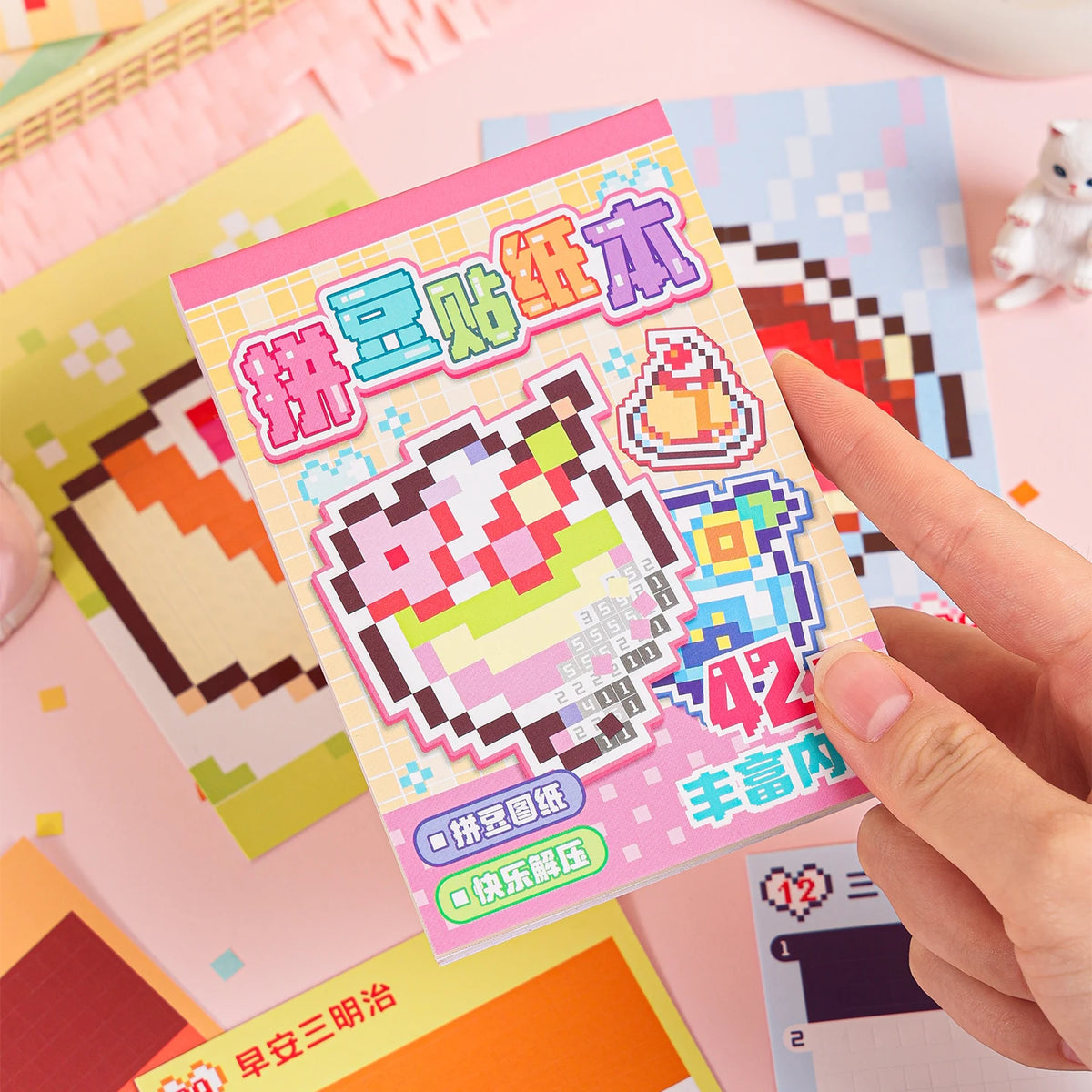 A hand holds a colorful set of handmade cartoon mini bean die cut stickers featuring pink and yellow designs.