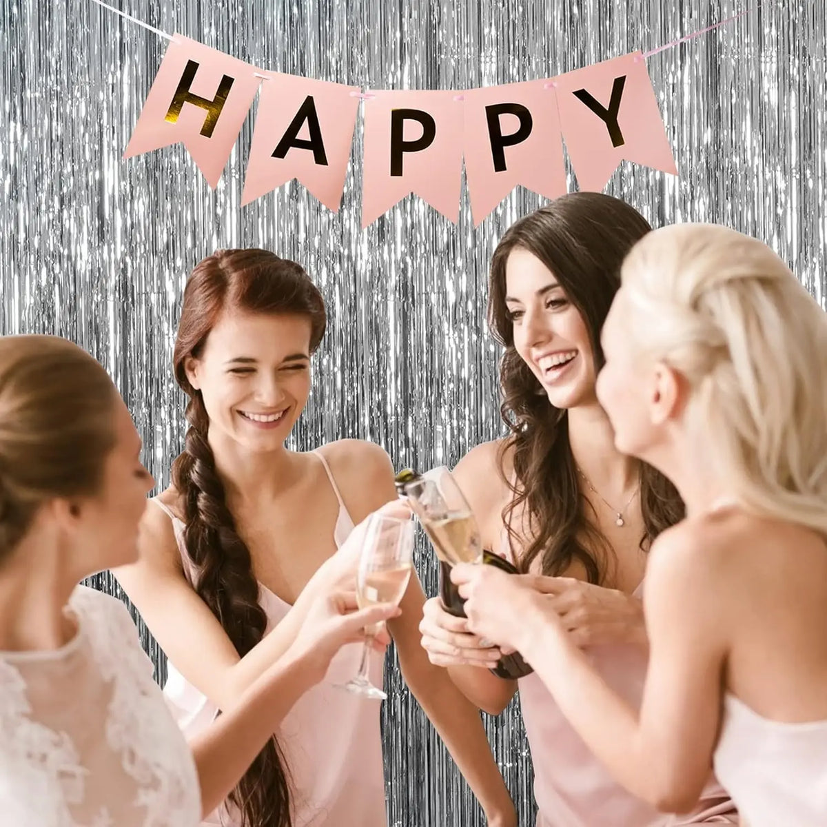 Three women toast with champagne in front of a pink banner backdrop
