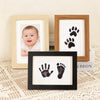 A set of wooden photo frames displaying baby and pet paw prints.