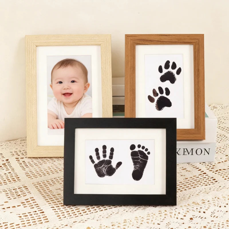 A set of wooden photo frames displaying baby and pet paw prints.