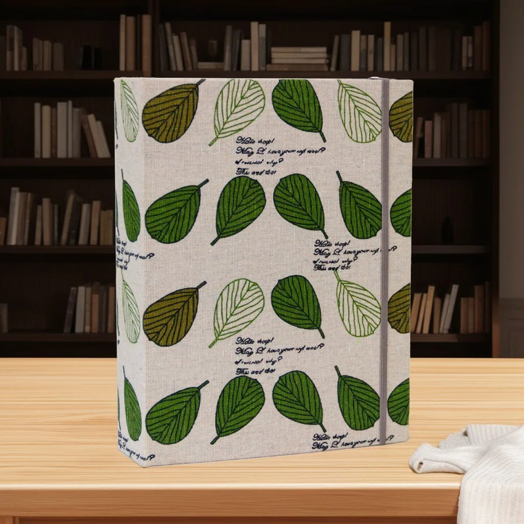 Hartcover Fotobuch mit hellbeiger, grünblättriger Oberfläche auf einem Holztable