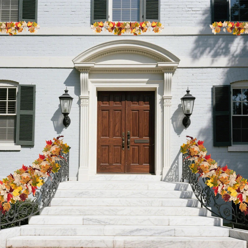 A white clapboard house entrance decorated with autumn maple leaf garlands on the steps and around the doorway.