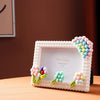 A pink photo frame decorated with colorful foam blocks and greenery, featuring the text Pin Living.