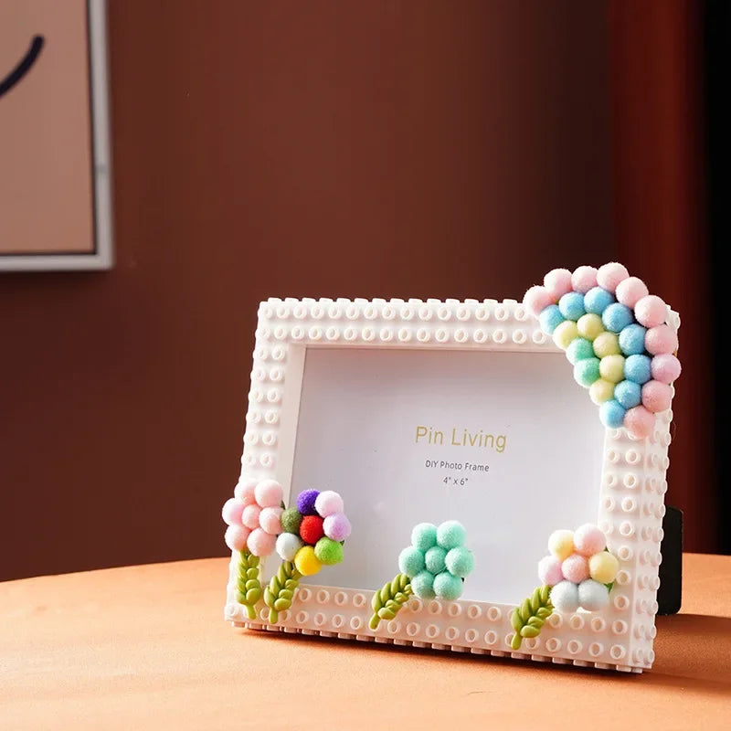 A pink photo frame decorated with colorful foam blocks and greenery, featuring the text Pin Living.