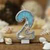 Glitter number cake topper shaped like the number 2 featuring a blue gemstone and a starfish design