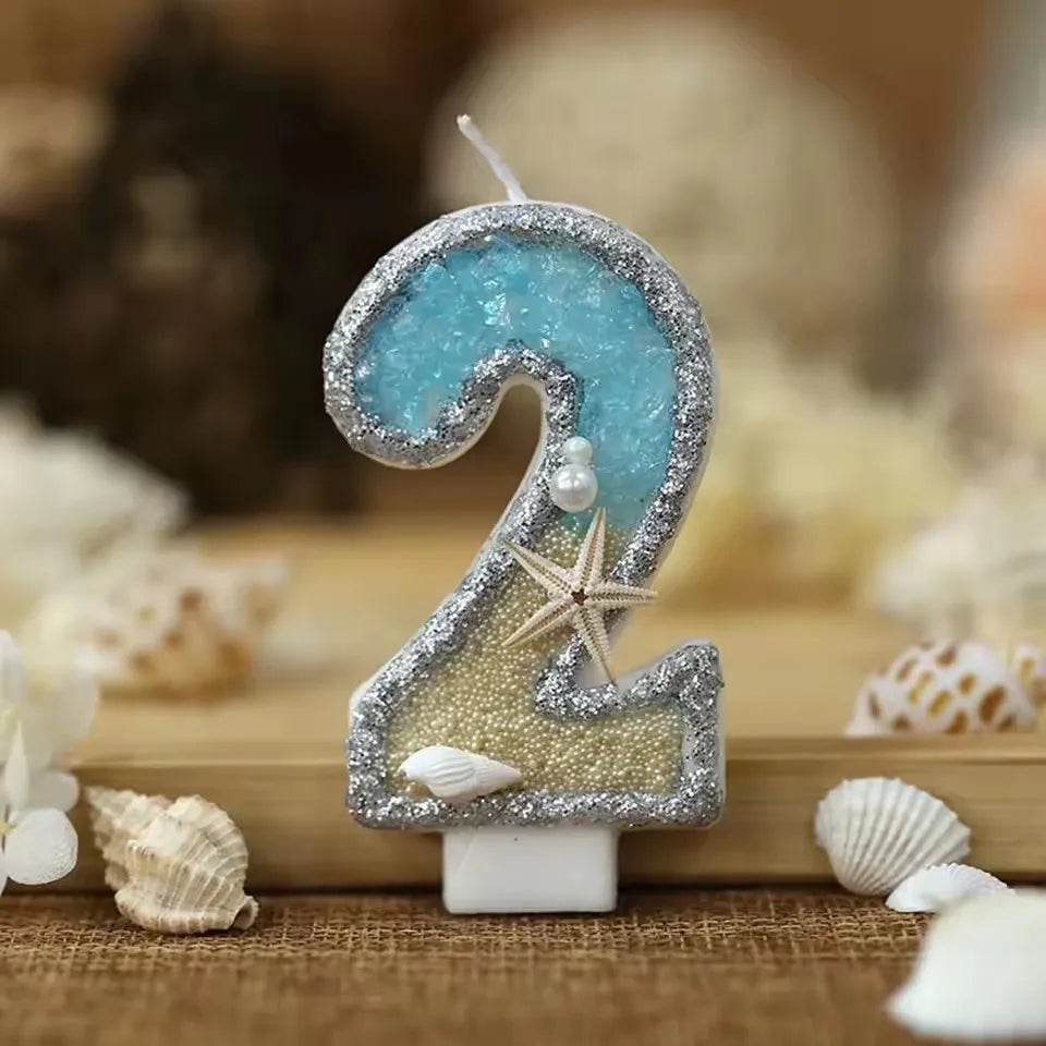 Glitter number cake topper shaped like the number 2 featuring a blue gemstone and a starfish design