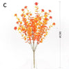 A bouquet of bright orange artificial fall flowers displayed in a clear glass vase.