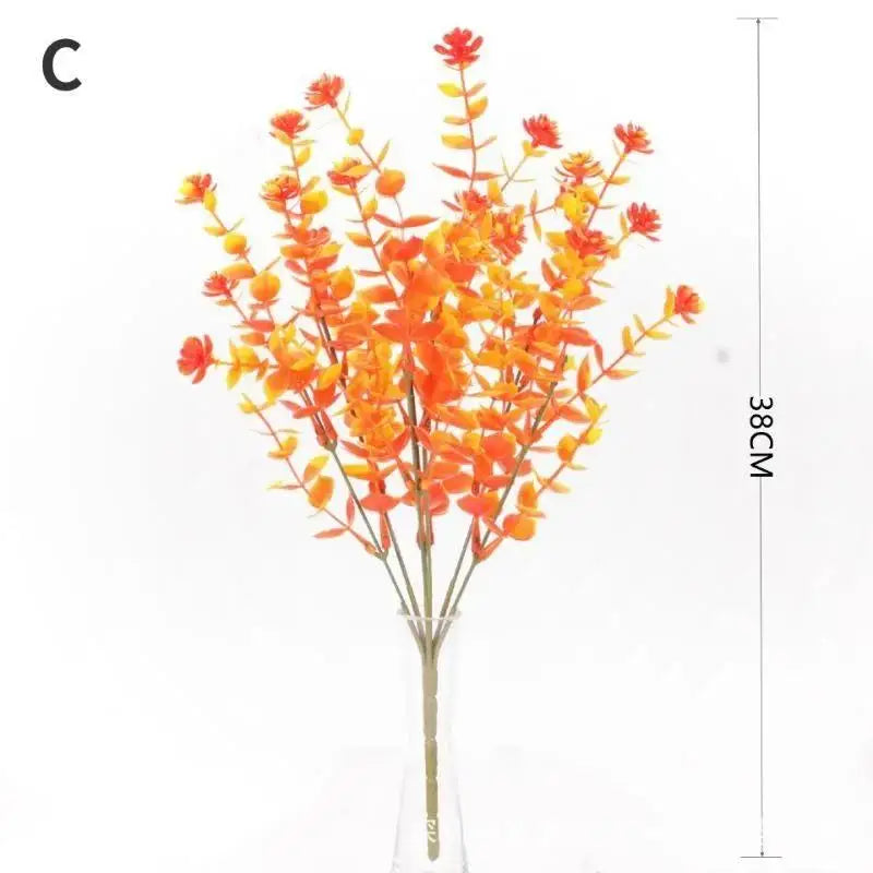 A bouquet of bright orange artificial fall flowers displayed in a clear glass vase.