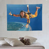 A vibrant tapestry featuring a smiling man in an orange and yellow outfit making a thumbs-up gesture against a blue ocean bac