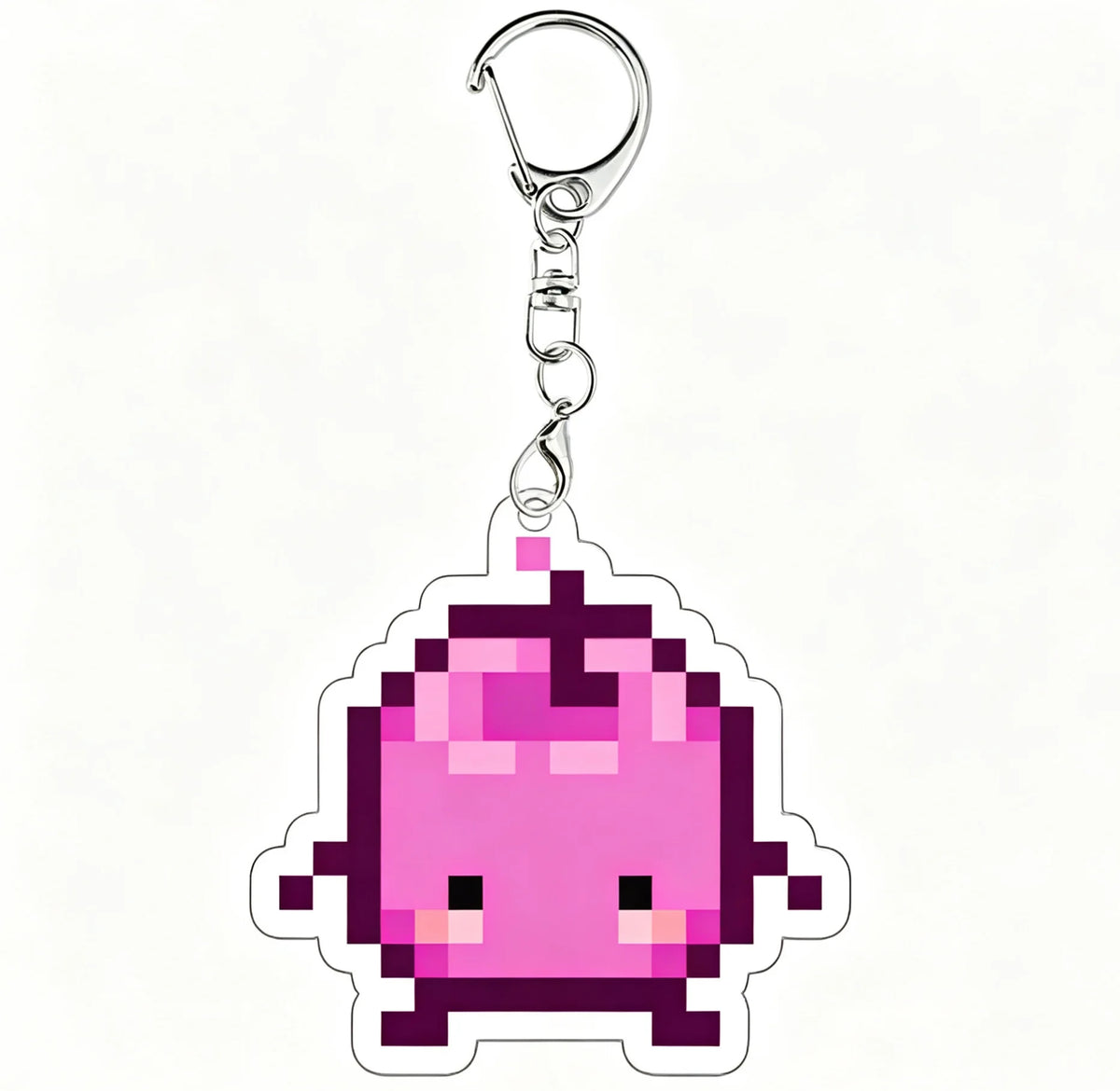 A pink pixel art charm of a Junimo character attached to a silver keychain ring.