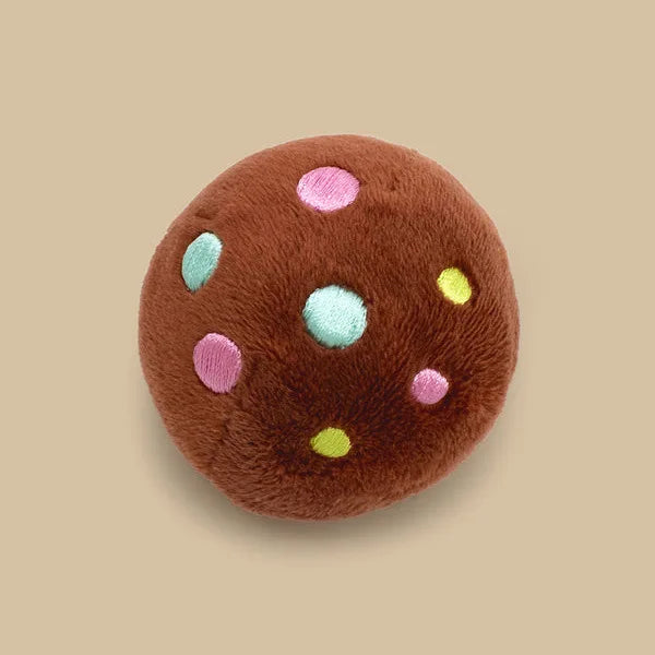 A round brown plush toy resembling a chocolate chip cookie with colorful dots.