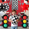 A child holds a black and white checkered race car traffic light balloon set against a red background.