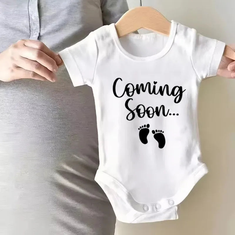 White baby bodysuit with black text that reads Coming Soon
