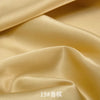 Close-up of smooth, golden satin fabric draped and folded