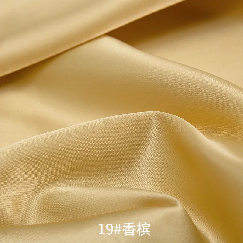 Close-up of smooth, golden satin fabric draped and folded