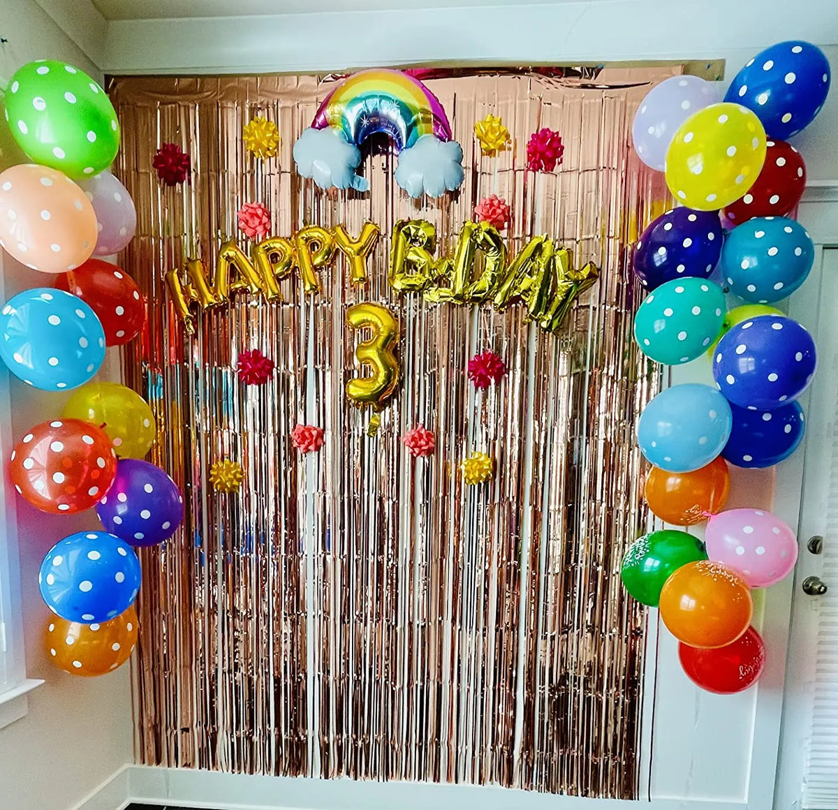 A metallic tinsel foil fringe curtain backdrop for parties featuring balloons and a happy birthday sign.