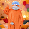 An orange plush monster loungewear romper with large eyes and a blue fuzzy head is shown.