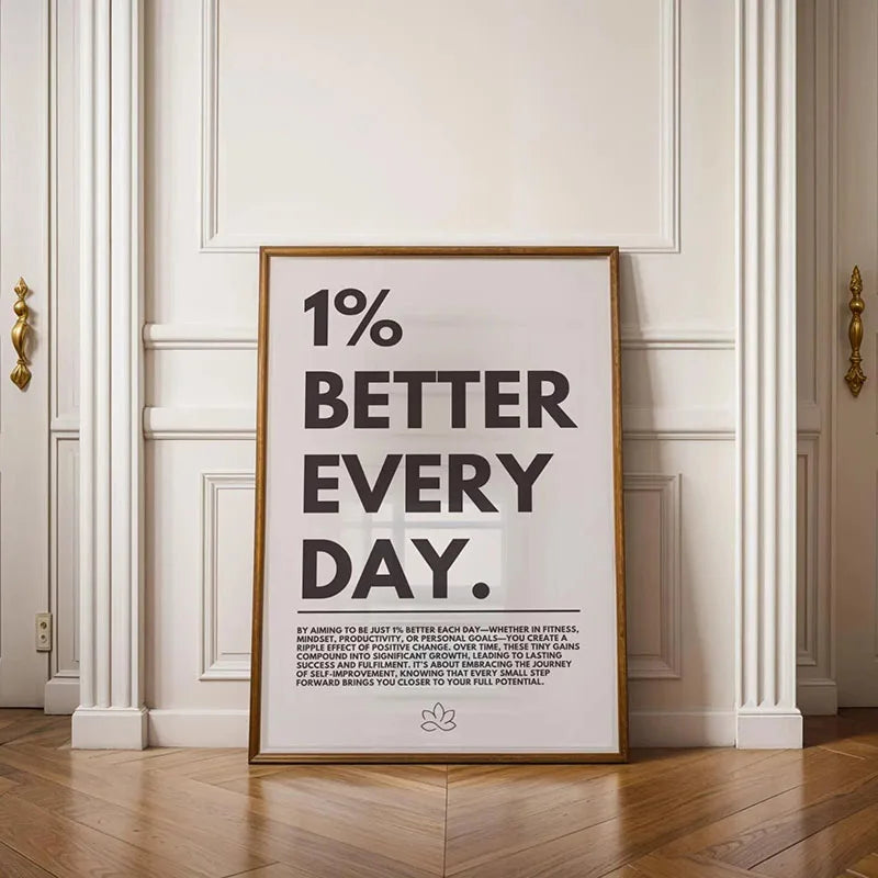 A framed quote on canvas reads One percent better every day set against a white wall with classical molding.