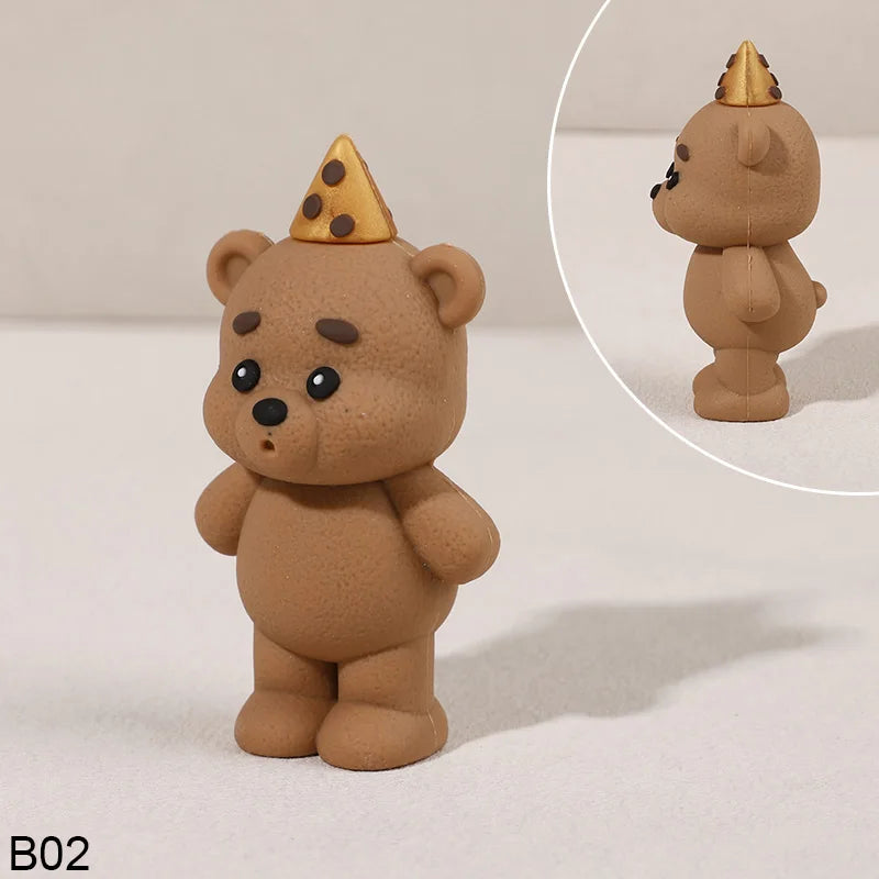 A small, light brown teddy bear figurine with a gold crown topper.