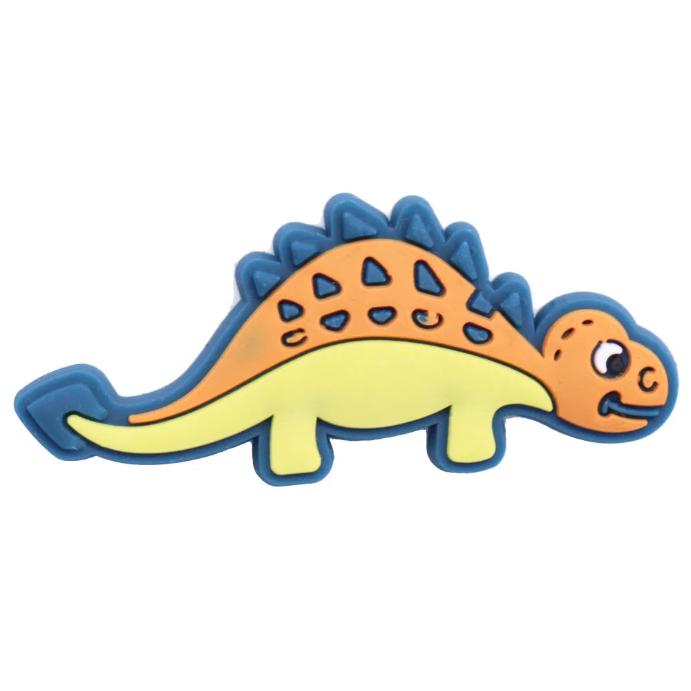 A set of twelve cartoon dinosaur PVC shoe charms featuring orange and yellow colors.
