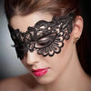 A close-up of a woman wearing an elegant black lace masquerade mask with intricate detailing.