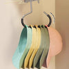 A rack of round multi-purpose closet hooks hanging from a metal bar, displaying various colored hats and scarves.