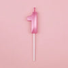 A single pink number candle shaped like the numeral one against a light pink background.