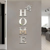 Silver butterfly letter wall mirror decals spelling out HOME on a gray wall.