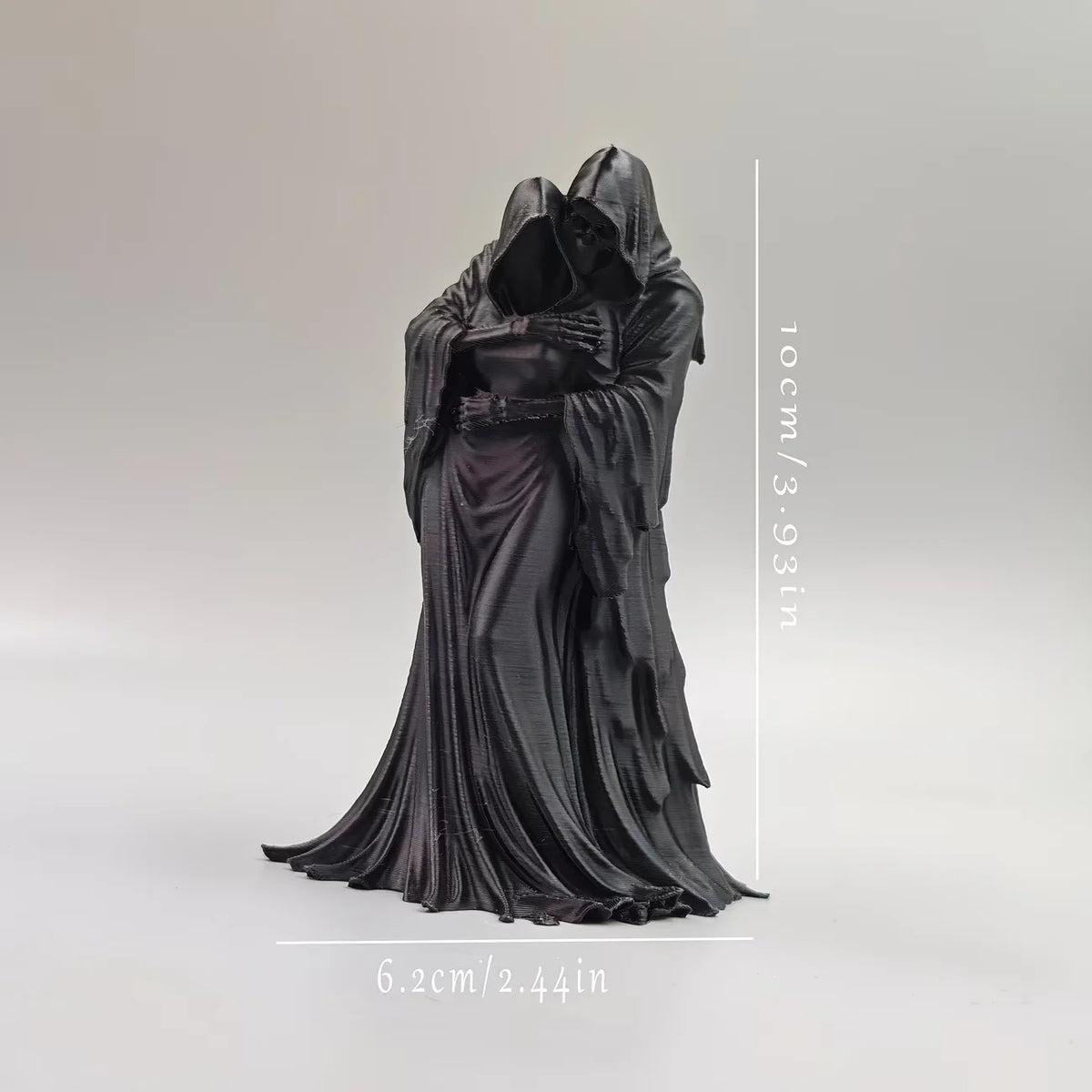 A black gothic statue of a figure embracing, draped in flowing fabric.