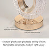 A close-up view of an oval crystal table lamp with a gold finish and clear glass texture, showing touch switch and dimming fe