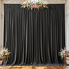 A dark gray fabric backdrop with vertical pleats decorated with a floral arrangement.