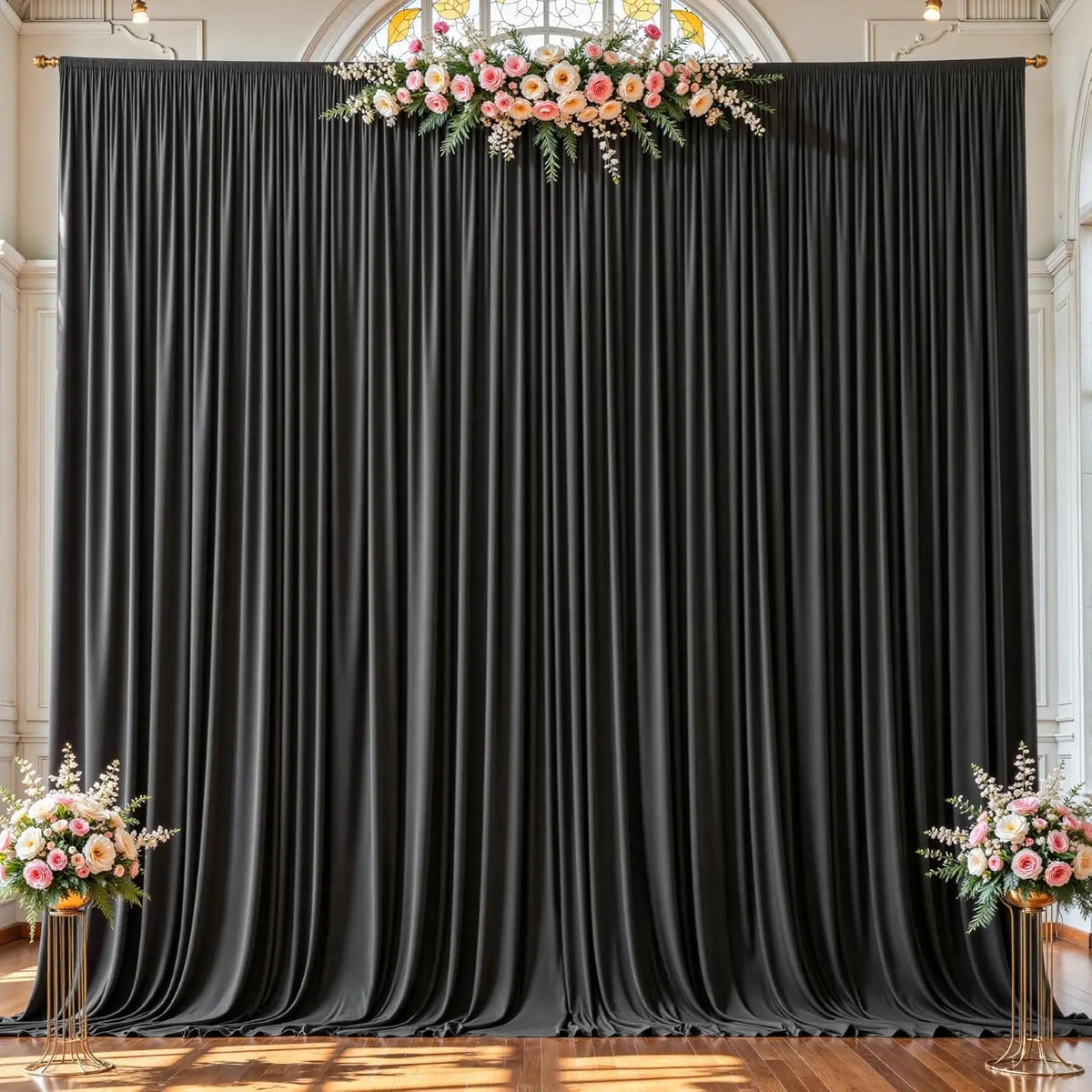 A dark gray fabric backdrop with vertical pleats decorated with a floral arrangement.