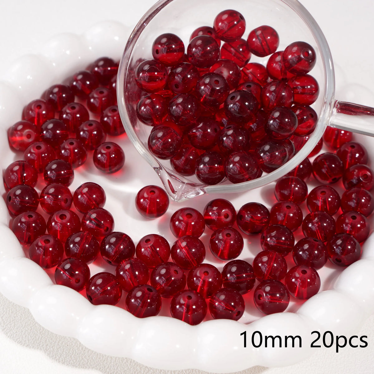 A clear glass bowl filled with 20 red round beads for jewelry making