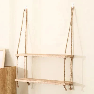 Rustic wooden hanging shelves with rope mounted on a white wall.