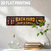 A vintage metal sign with the text Backyard Bar & Grill is mounted on a white wall.