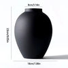 A matte black ceramic vase with a rounded body shown from the side.