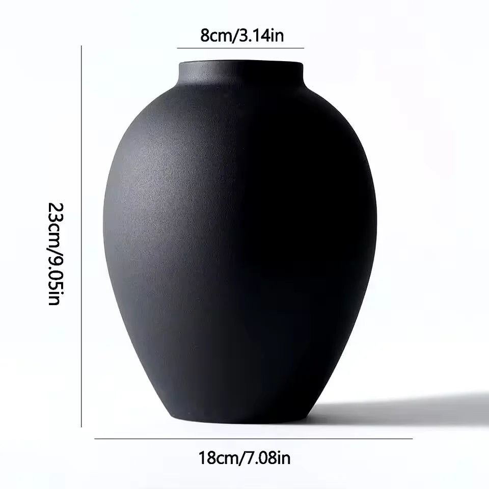 A matte black ceramic vase with a rounded body shown from the side.
