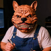 A person wearing a realistic cute alien full-face latex mask and denim overalls.