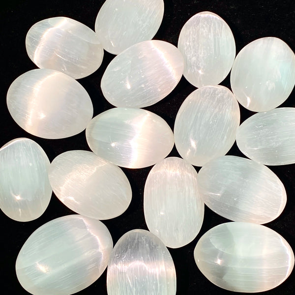 A collection of oval, translucent white to pale green selenite palm crystals.