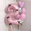 A cluster of pink and silver balloons shaped like the number 2, tied with black bows.