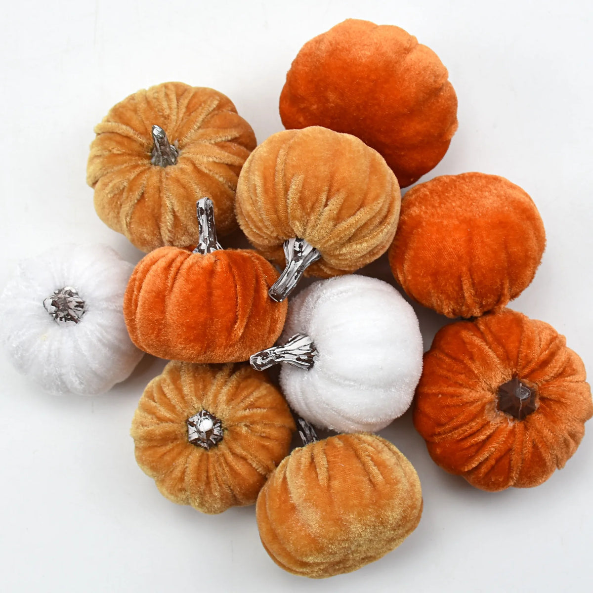 A set of ten velvet pumpkin decorations in shades of orange and gold for fall and holiday styling.