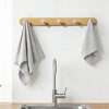 A modern kitchen sink setup featuring a stainless steel sink and faucet mounted on a wooden wall hook rack.