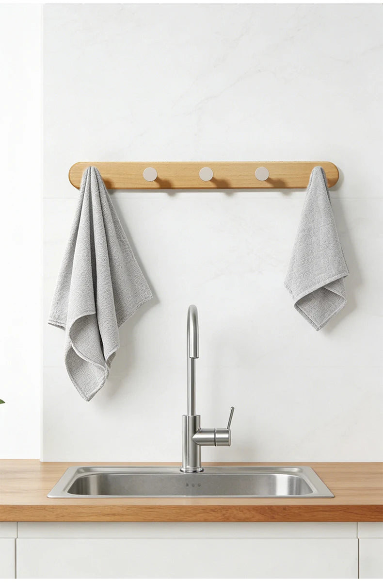A modern kitchen sink setup featuring a stainless steel sink and faucet mounted on a wooden wall hook rack.