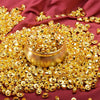 A pile of gold-colored metal prosperity decorations set resting on a deep red fabric.