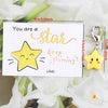 An inspirational card with a yellow star design and a matching gold-colored star keychain.