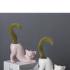 A white ceramic cartoon cat succulent planter with a curved tail design, shown next to a small white box.