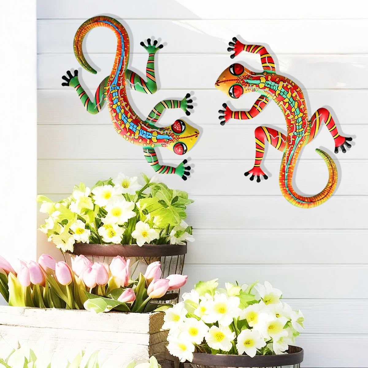 Handcrafted metal gecko wall art featuring colorful, stylized geckos against a white wooden background with flowers.