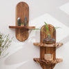 Two wooden wall shelves display crystals and a small plant on a white wall.