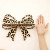 A leopard print bow-shaped wall mounted storage rack is displayed against a white background.